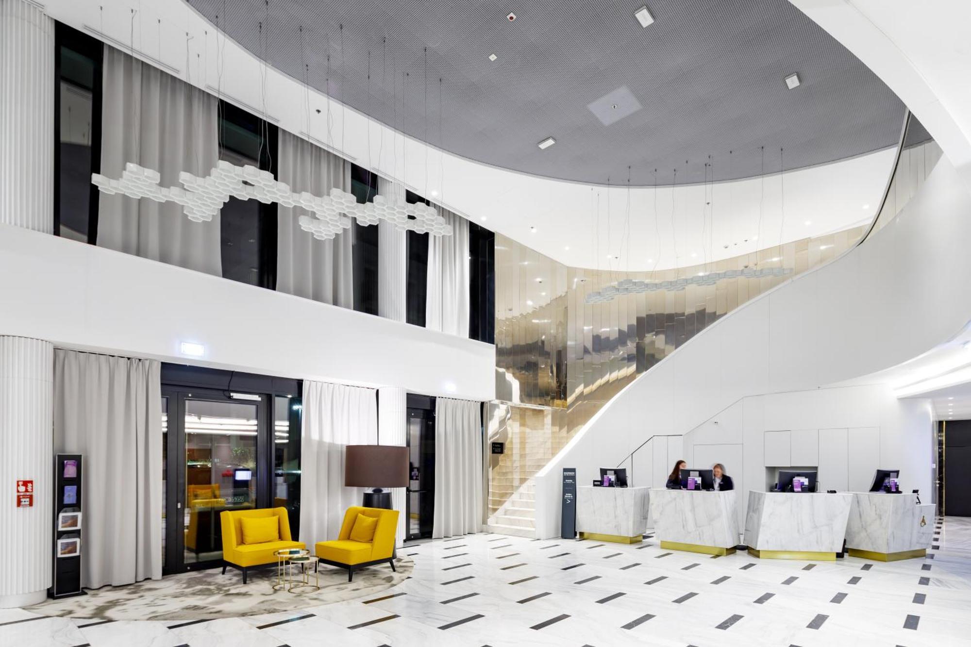 Radisson Blu Resort Świnoujście Zewnętrze zdjęcie The photo shows a modern interior space, likely a hotel or a lobby area. It features a spacious, open design with high ceilings and a stylish staircase that leads to an upper level. The walls are mostly white, with large windows allowing natural ligh