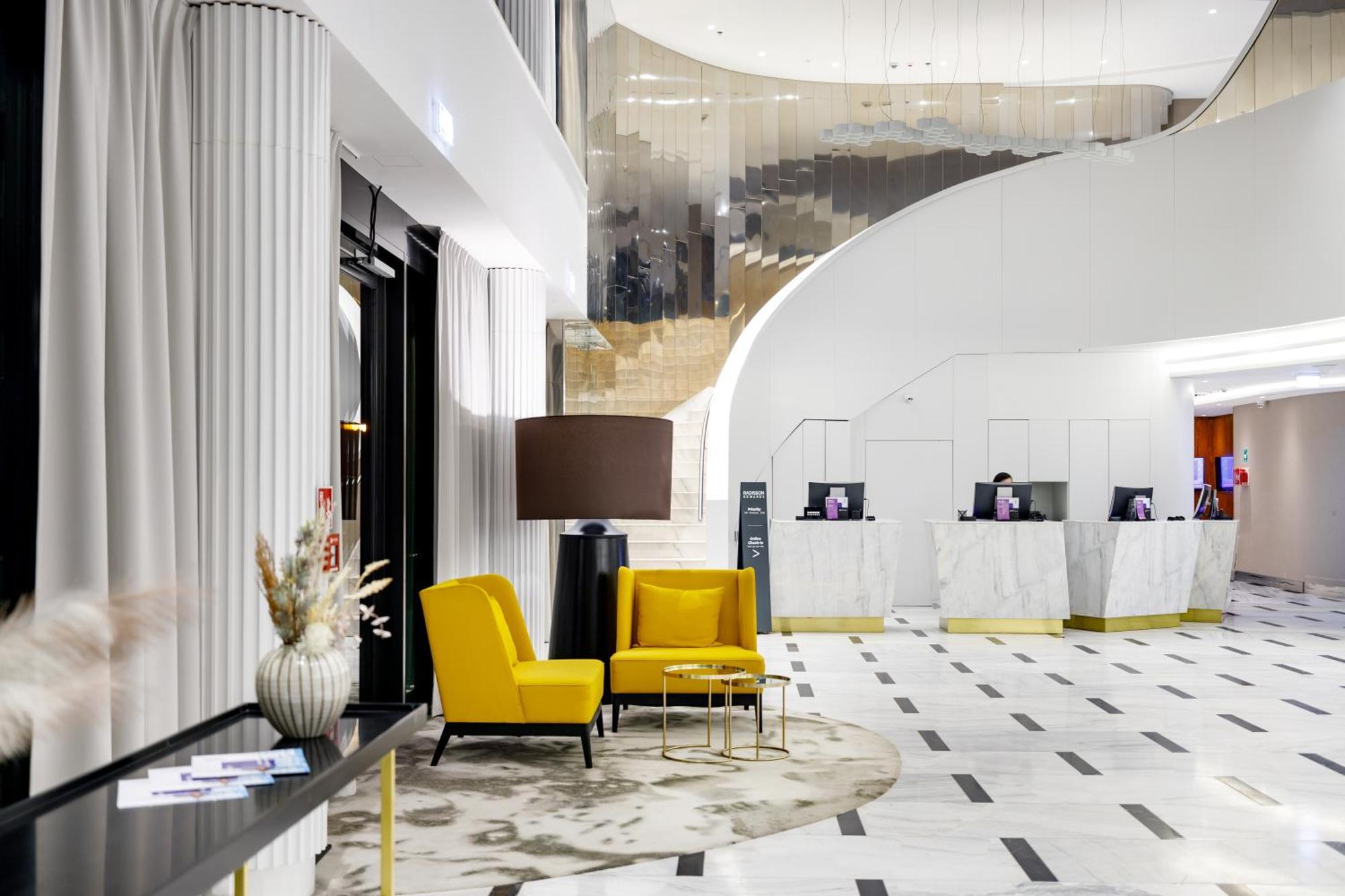 Radisson Blu Resort Świnoujście Zewnętrze zdjęcie The photo shows the interior of a modern hotel lobby. The space features a stylish design with a combination of yellow and neutral-colored seating, including two yellow armchairs and a small table. In the background, there is a reception area with ma