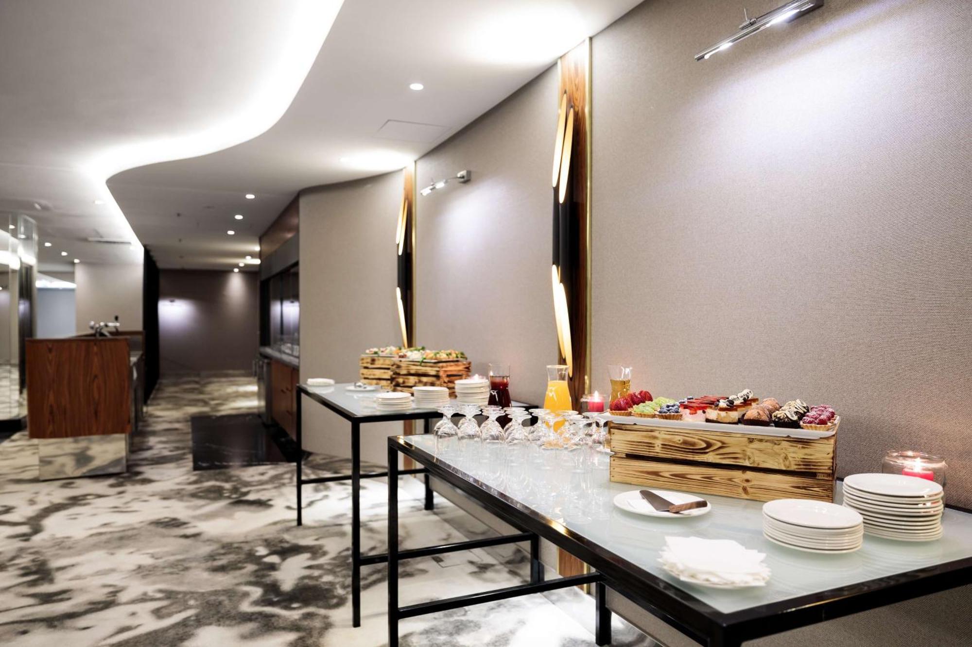 Radisson Blu Resort Świnoujście Zewnętrze zdjęcie The photo showcases a modern, elegantly designed banquet or catering area. There are sleek tables set up, featuring a variety of food displays. One table appears to have a wooden crate filled with assorted fruits and pastries, while the other table s