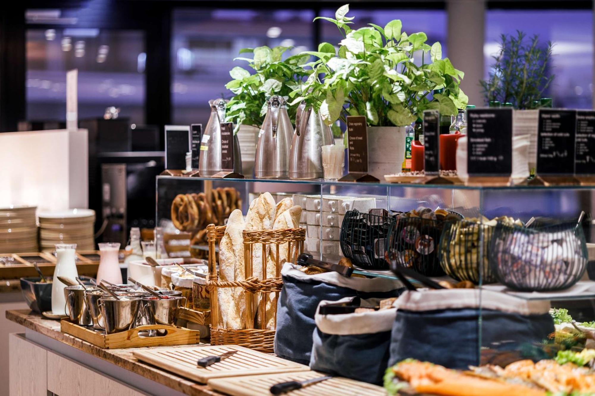 Radisson Blu Resort Świnoujście Zewnętrze zdjęcie The photo depicts a beautifully arranged buffet or food display area. It features various items such as:

- Several glass or metal containers, possibly holding beverages or condiments.
- Fresh greenery in pots, suggesting a focus on natural elements.