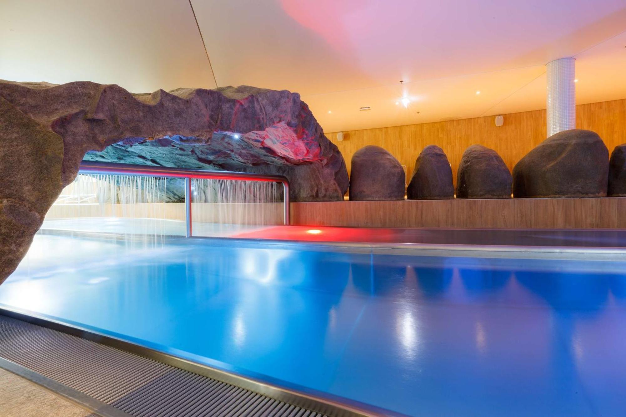 Radisson Blu Resort Świnoujście Zewnętrze zdjęcie The photo shows a serene indoor swimming pool area. The pool has clear blue water, and there is a distinctive rock formation that resembles a cave on one side. Soft lighting enhances the atmosphere, casting a gentle glow across the space. In the back